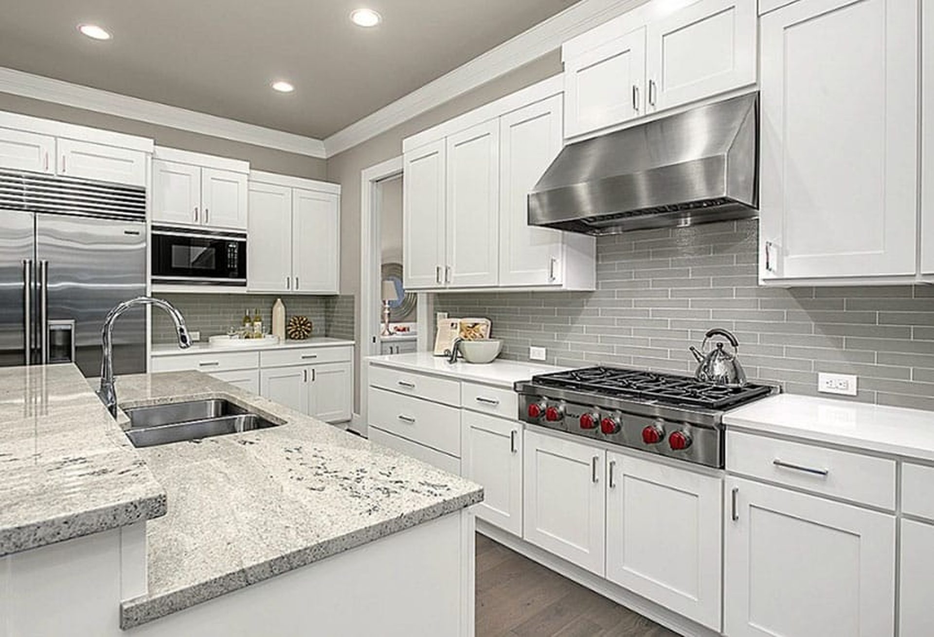 White flat panel kitchen with marble surfaces and stainless hood